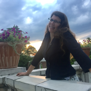 photo of Jennie Stokum against a setting sun next to a flowering plant